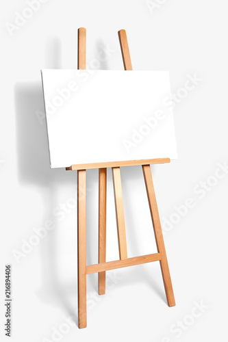 pure white synthetic canvas stretched on a wooden stretcher standing on a wooden easel for artists. Gray monophonic background. Art, creativity, hobby, job and creative occupation concept