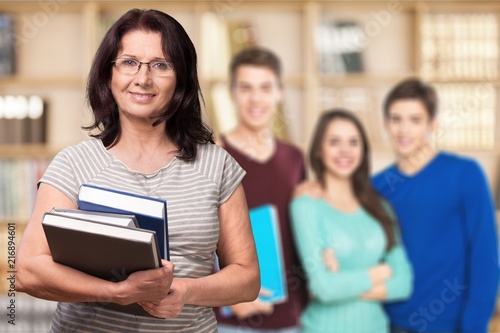 Mature woman teacher with books in library
