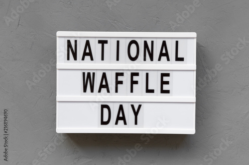 'National Waffle Day' word on lightbox over concrete background, top view. From above, overhead. © Liudmyla