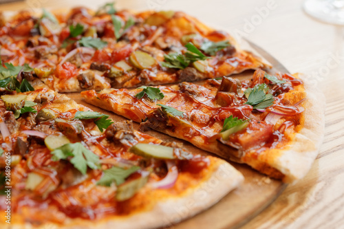 Pizza with meat, BBQ sauce, pickled cucumbers and parsley