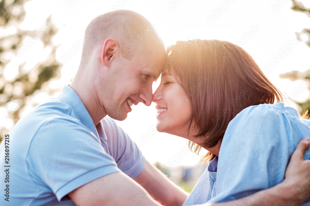 Young loving couple outdoors sitting on grass, hugging and looking on each other with love. Young loving couple outdoors sitting on grass, hugging and looking on each other with love.