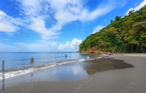 Black Sand beach in Martinique, Caribbean. Anse Couleuvre, Le Precheur Region, near Motagne Pelee. People in water looking to turtles. photo