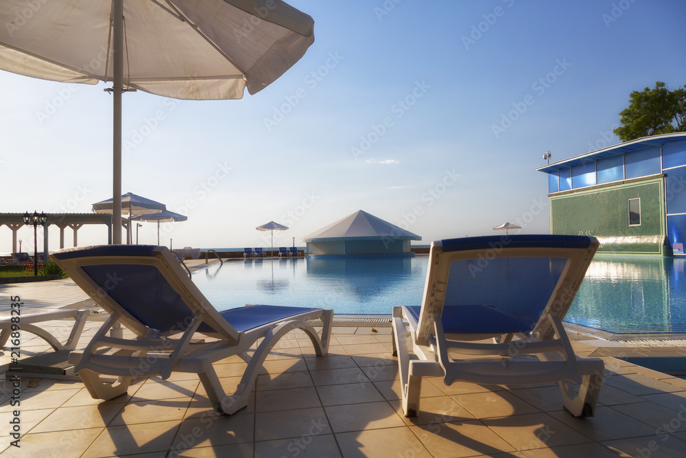 Fototapeta premium Chaise lounges at pool in hotel