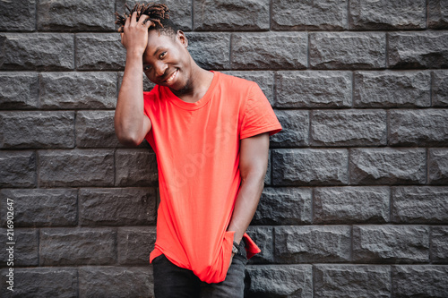 African male model standing in empty red t-shirt against brick wall