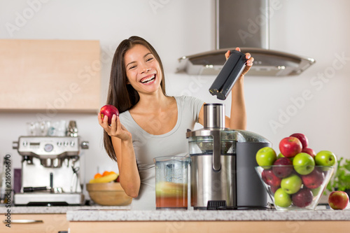 Vegetable juice healthy food juicer machine- Asian woman juicing green and red apple fruits as part of her wellness food, detox smoothie. Beautiful happy mixed Asian woman with juice maker in kitchen. photo
