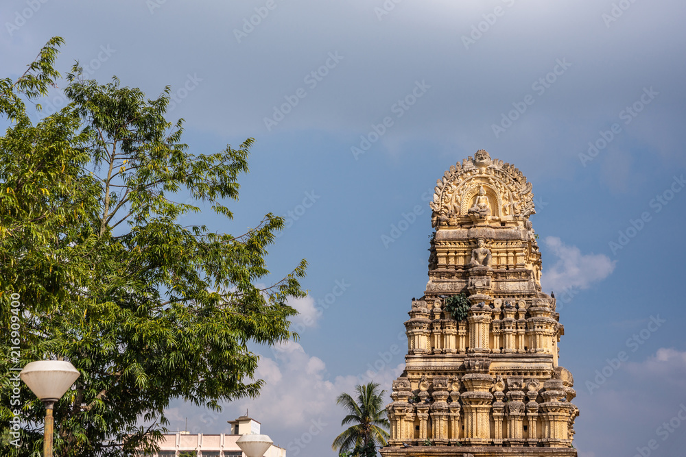 Shravanabelagola, Karnataka, India - November 1, 2013: Brown stone Gopuram at entrance to Kalyani sacred pond against blue sky. Green tree in photo.