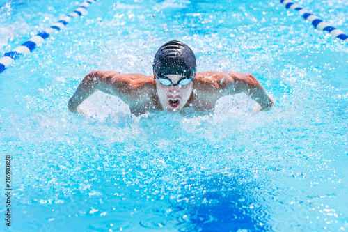 Fototapeta Teenage swimmer swimming butterfly stroke in a race
