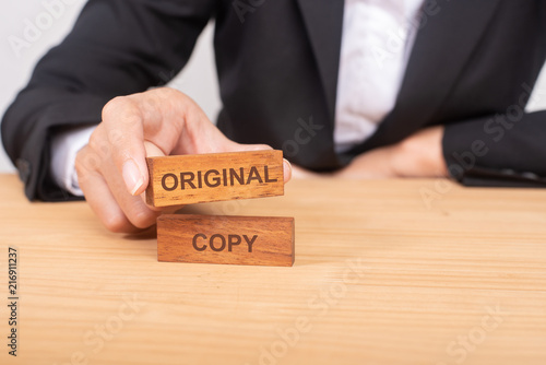 Hand of businessman choosing wood blog with icon and word Original and Copy