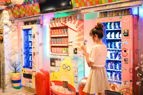 Roiet, Thailand - 26 Dec, 2016 :  an unidentifed woman posting in front of Colorful Japanese vending machines photo