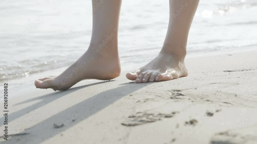 Female legs barefoot walks at the sea on the splashing waves. 4K Female legs barefoot walks at the sea on the splashing waves. 4K