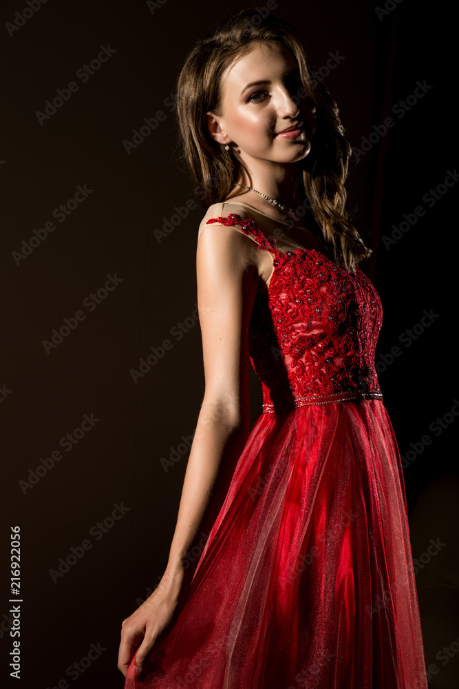 Sensual beautiful young woman posing in red dress in dark room. professional make-up Sensual beautiful young woman posing in red dress in dark room. professional make-up