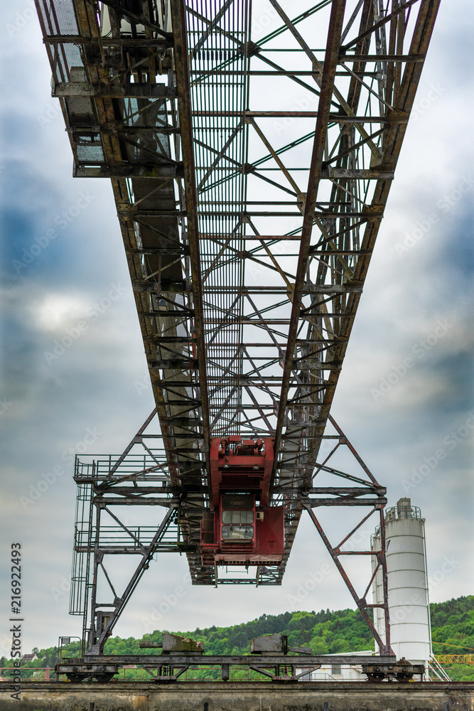 ein alter rostiger ausgedienter Portalkran. Der Kran zeigt sich vor einem bewölkten Himmel. Die rote Kabiene steht markant heraus. ein alter rostiger ausgedienter Portalkran. Der Kran zeigt sich vor einem bewölkten Himmel. Die rote Kabiene steht markant heraus.