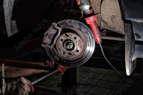 Mechanic with dirty hands from lubricant. engaged in repair of the brake system of the car photo