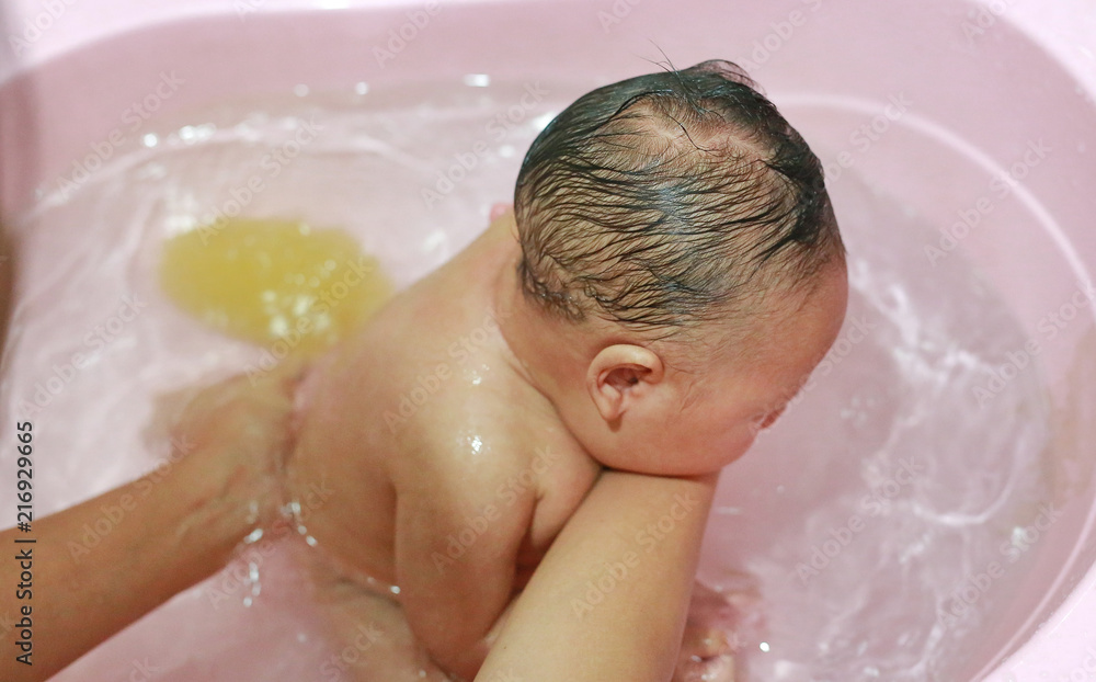 Close up hands of mother taking a bath to her newborn baby in a bathtub. Close up hands of mother taking a bath to her newborn baby in a bathtub.