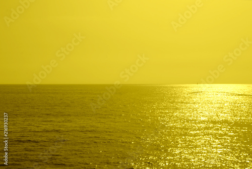 Summer minimalist background  yellow monochromatic glittering sunset on the sea