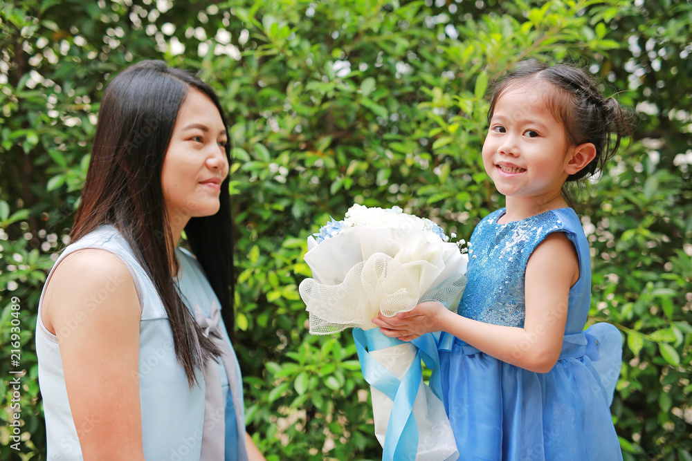 Asian child girl giving bouquet of flowers for her mother in the garden.