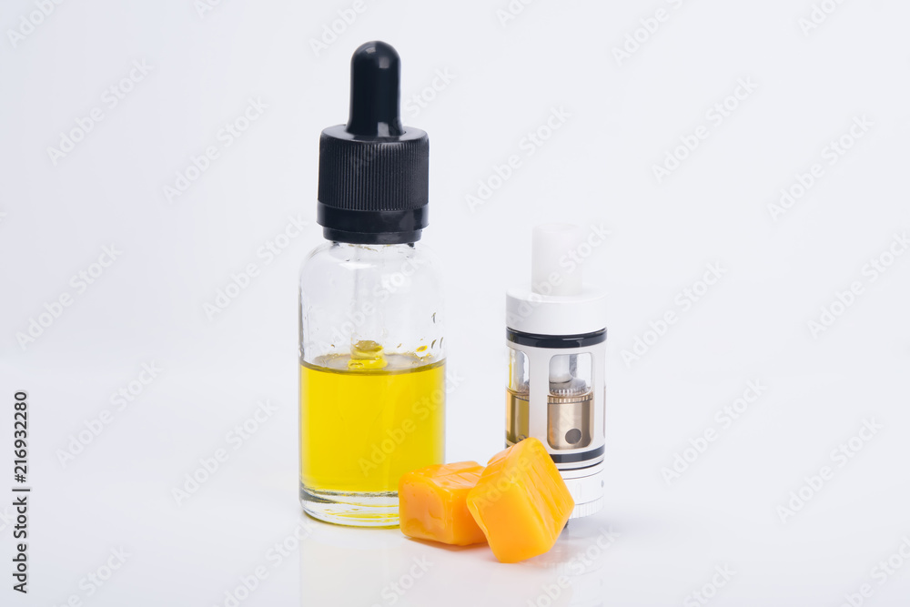 on a light background stands a bottle of yellow liquid for e-cigarettes, with a taste of candy on a light background stands a bottle of yellow liquid for e-cigarettes, with a taste of candy