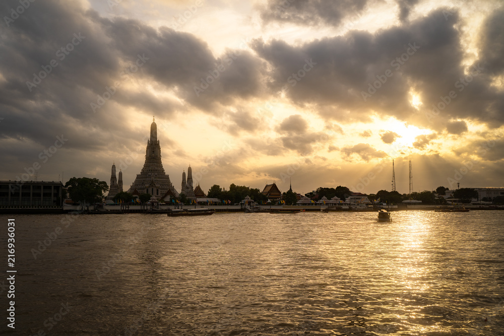 Wat Arun Temple Beside Chao Phraya River with Beautiful Sunshine Through the Cloud, Bangkok, Thailand. One of the Most Famous Place of Thailand's Landmarks.