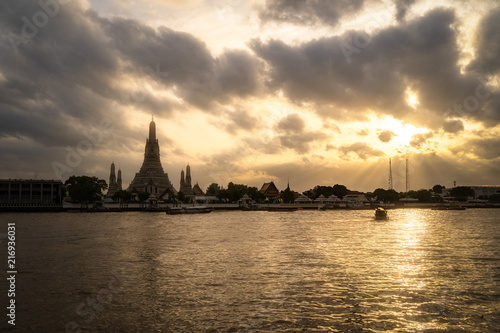 Wat Arun Temple Beside Chao Phraya River with Beautiful Sunshine Through the Cloud, Bangkok, Thailand. One of the Most Famous Place of Thailand's Landmarks.