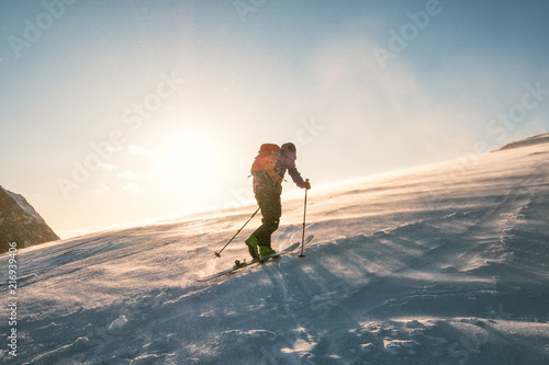 Man skier with backpack trekking on snow mountain with sunlight photo