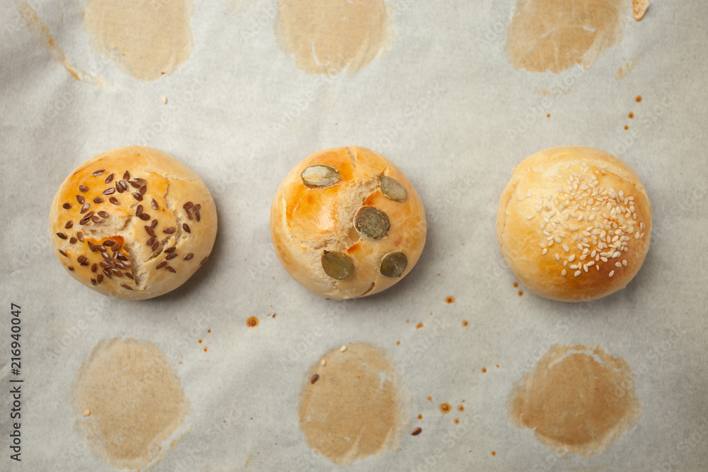 Homemade burger bun on bakery parchment . Food photography, concept of homemade fresh bakery. Rolls with sesame seeds hamburger with sesame, pumpkin, flax, sunflower seeds Homemade burger bun on bakery parchment . Food photography, concept of homemade fresh bakery. Rolls with sesame seeds hamburger with sesame, pumpkin, flax, sunflower seeds