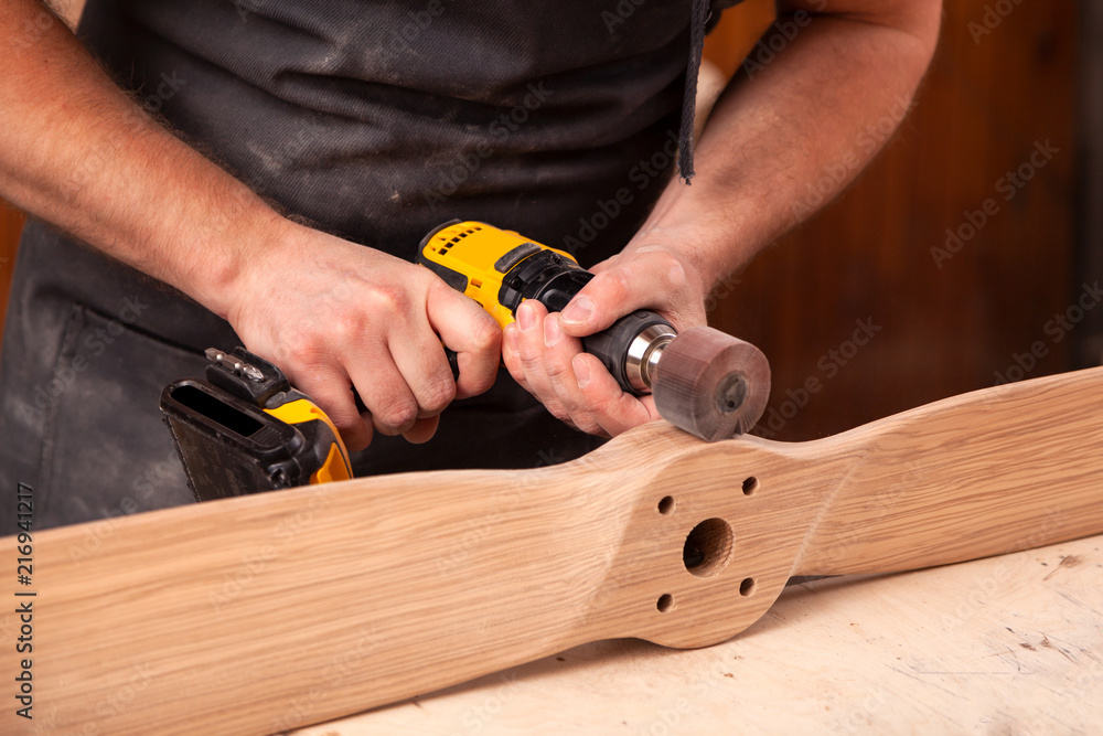 Close up of an young man builder carpenter equals polishes wooden board with a polishing machine or random orbit sander in the workshop Close up of an young man builder carpenter equals polishes wooden board with a polishing machine or random orbit sander in the workshop