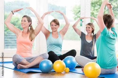 Happy moms in postnatal regression course doing yoga asana photo