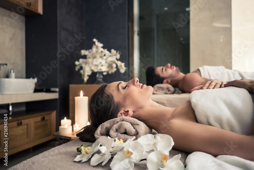 Młody mężczyzna i kobieta leżą na łóżkach do masażu w azjatyckim luksusowym spa i centrum odnowy biologicznej