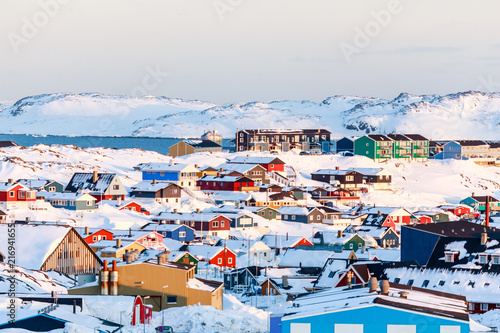 Lots of Inuit houses scattered on the hill in Nuuk city covered in snow with sea and mountains in the background, Greenland photo