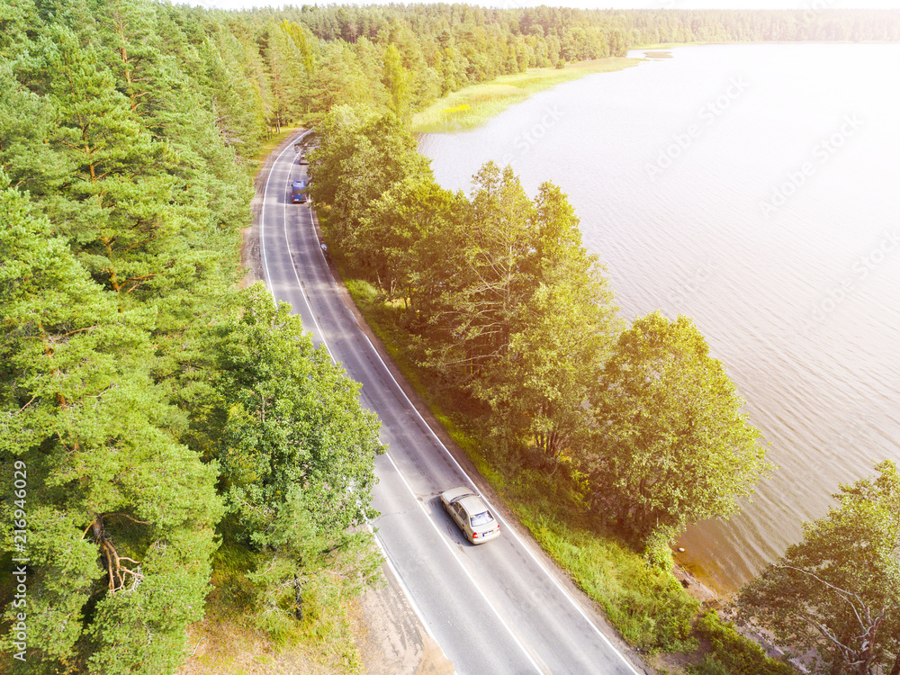 Aerial view of highway with car. Aerial view of a country road with moving car. Car passing by. Aerial road. Aerial view flying. Captured from above with a drone. Soft lighting