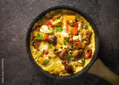 Frittata with meat and vegetables on dark background.