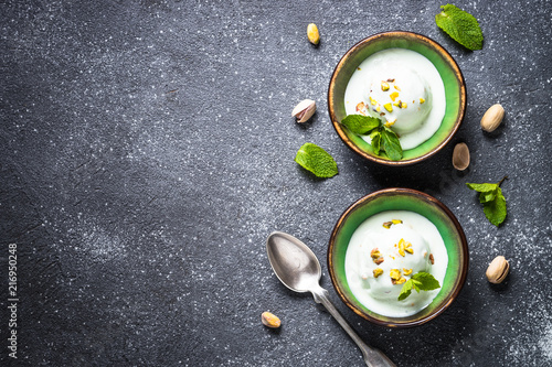 Canvas Print Pistachios ice cream in bowls on black stone table.