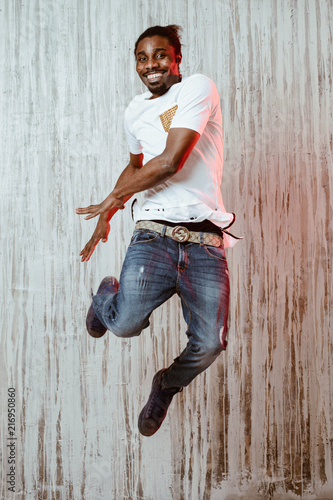 Ethnic man jumping and smiling near wall photo