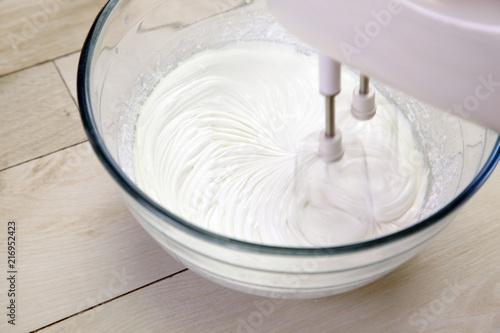  cream / Whipping cream mixer in a glass bowl on wooden table