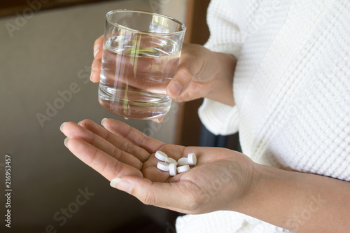 Female hands hold medicine tablet and glass. Healthcare concept.