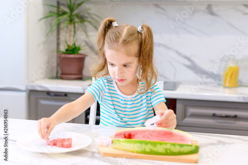 child eats watermelon. happy baby girl eating watermelon in summer in the kitchen. selective focus.