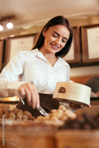 Confectionery. Woman Selling Chocolate Candies In Store photo