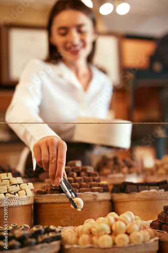 Confectionery. Woman Selling Chocolate Candies In Store photo