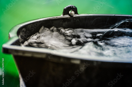 Rainy weather on the terrace in summer. The rain falls into the bucket and creates splashes.
