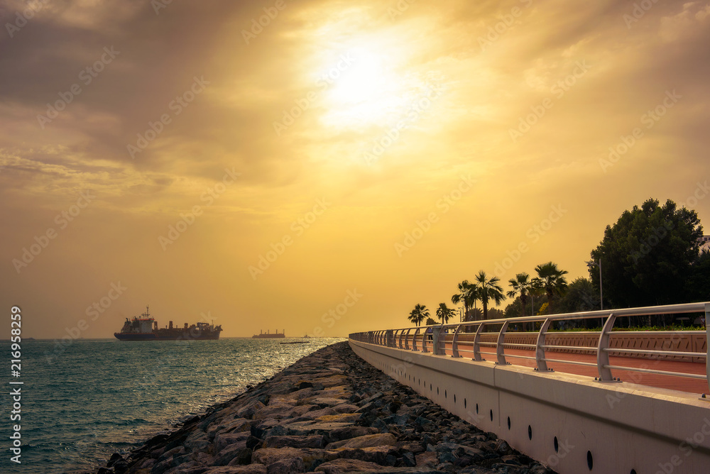 Cargo container ship leaving Dubai Marina at sunset