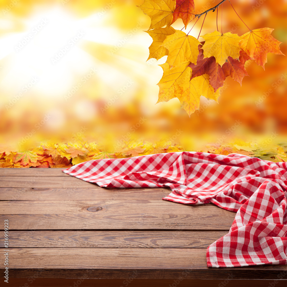 Obraz premium Red checkered tablecloth on wooden table. Napkin close up top view mock up. Autumn rustic background.