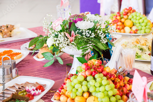 Served table at the Banquet. Fruits, snacks, delicacies and flowers in the restaurant. Solemn event or wedding.