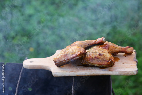 Grilled hot grilled chicken thighs on a grill on a wooden board with smoke around. outdoors. Free space for text photo