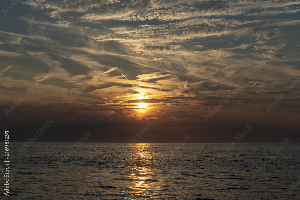 Golden sunset over the North Sea, seen from the beach of Ter Heijde, the Netherlands. A lot of contrails can be seen in the air. Golden sunset over the North Sea, seen from the beach of Ter Heijde, the Netherlands. A lot of contrails can be seen in the air.