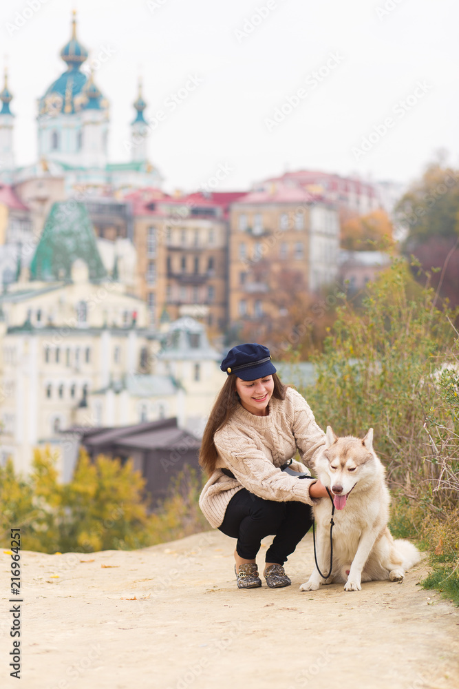 Smiling Hipster Girl with her Dog on the City background. Toned and Filtered Photo with Bokeh and Copy Space. Urban Youth Lifestyle Concept