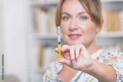 Woman is holding syringe with insulin or heparin