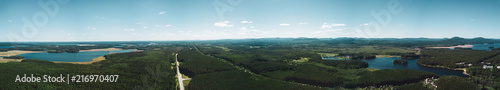 Aerial drone panoramic view of the land of lakes landscape, the road among the deep mixed forest, mountains on the background, long panoramic photo in summer evening in South Ural, Russia