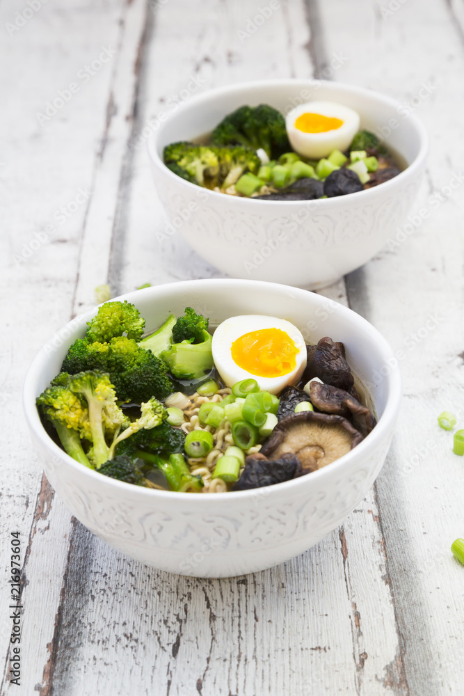 Two bowls of Ramen soup with egg, broccoli, noodles, shitake mushroom and spring onions Two bowls of Ramen soup with egg, broccoli, noodles, shitake mushroom and spring onions