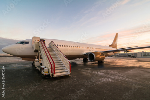 Passenger airplane parked at the airport. Commercial jet plane with sunset sky background, standing at the airport and waits for departure