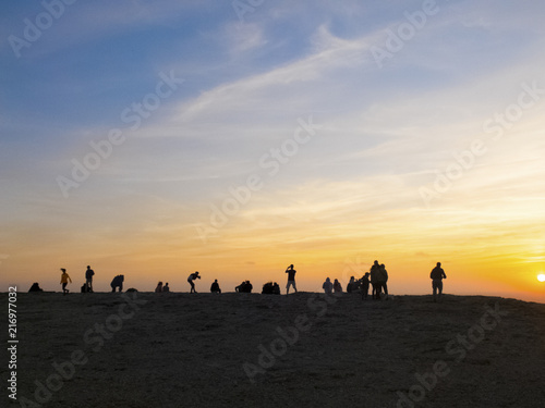 group of people in silhouette enjoy a colorful amazing sunset on the rocks. men and woman in outdoor leisure activity. vacation and see the world concept